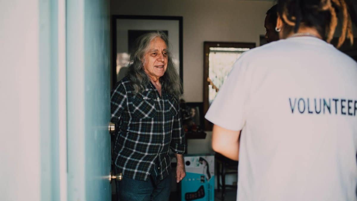 A volunteer visits an elderly person at home, creating a warm connection.