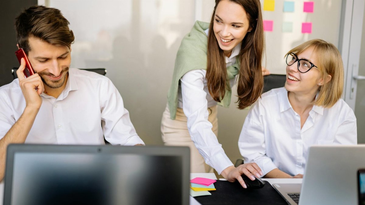 Business professionals collaborating at a meeting with laptops and notes in a modern office setting.