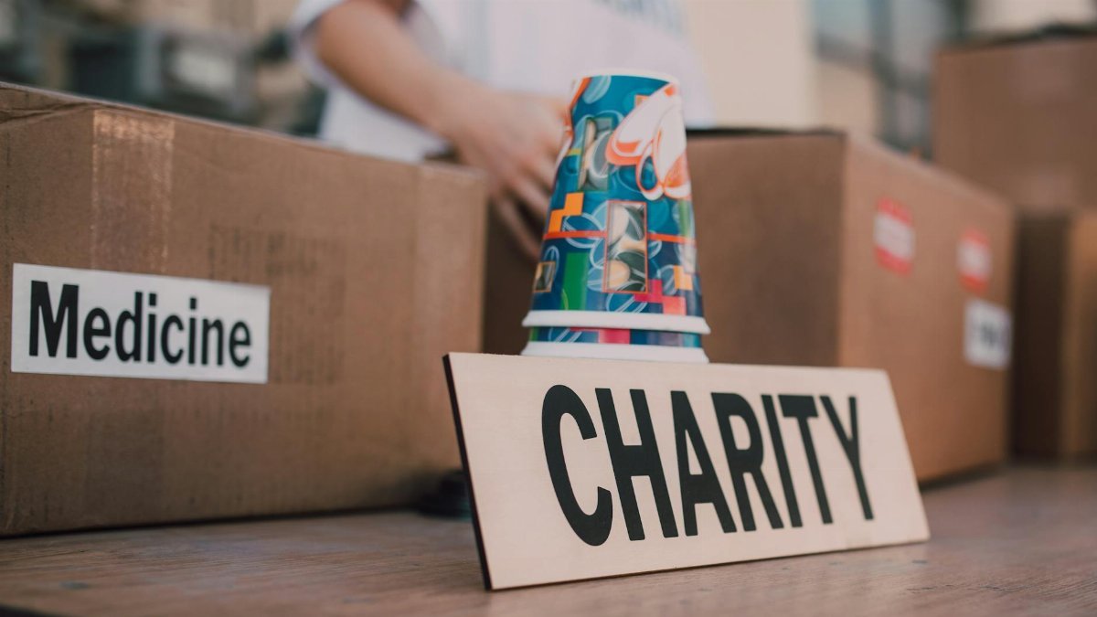 Close-up of charity boxes labeled for donation, featuring medicine and colorful paper cups.