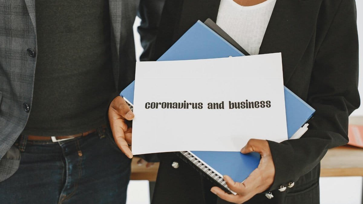 Business professionals hold a document about coronavirus impact with formal attire visible.