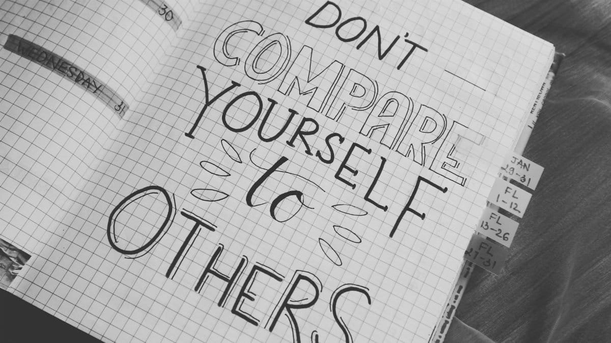 Black and white photo with motivational handwriting on a grid notebook page.