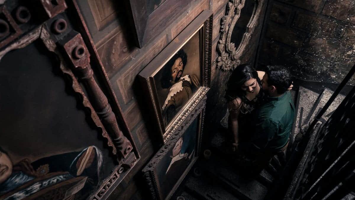 Asian couple in a vintage setting, surrounded by classic art, sharing an intimate moment on a staircase.