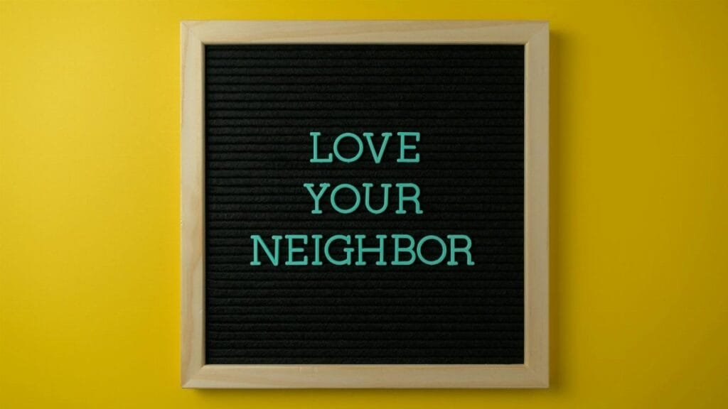 A motivational message "Love Your Neighbor" on blackboard against a yellow wall.