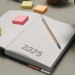 Open planner for 2025 with colorful sticky notes and plants on a desk.