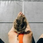 Woman practicing yoga on a mat outdoors, stretching on a sunny day.