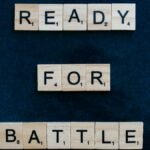 Scrabble tiles spell 'Ready for Battle' on a blue background, symbolizing motivation and readiness.