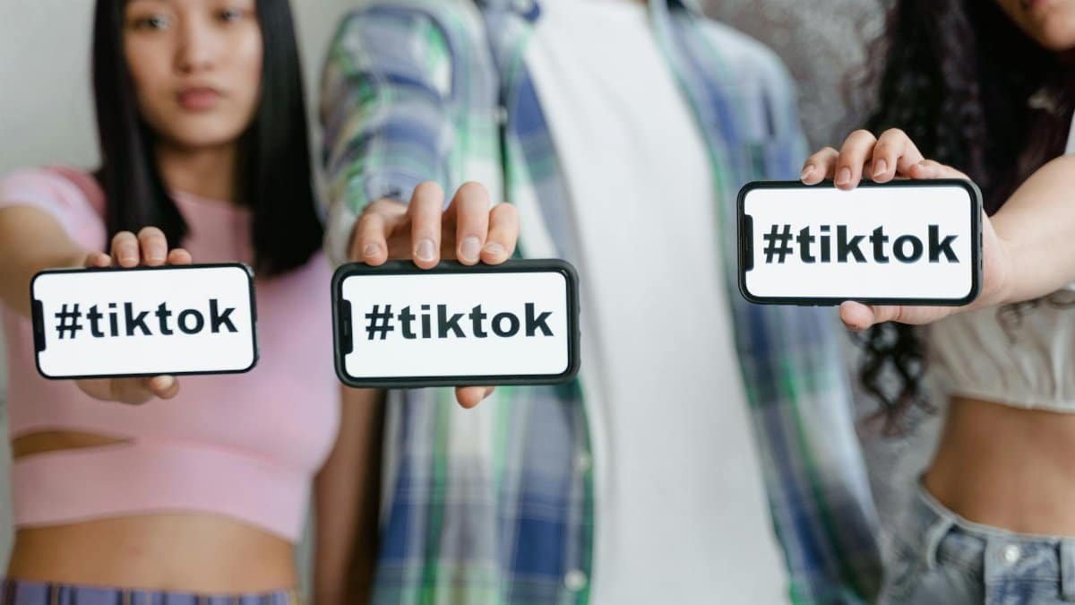Young adults holding smartphones with TikTok hashtag, showcasing social media engagement.