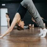 Caucasian woman practicing yoga pose in an indoor dance studio. Group class setting.