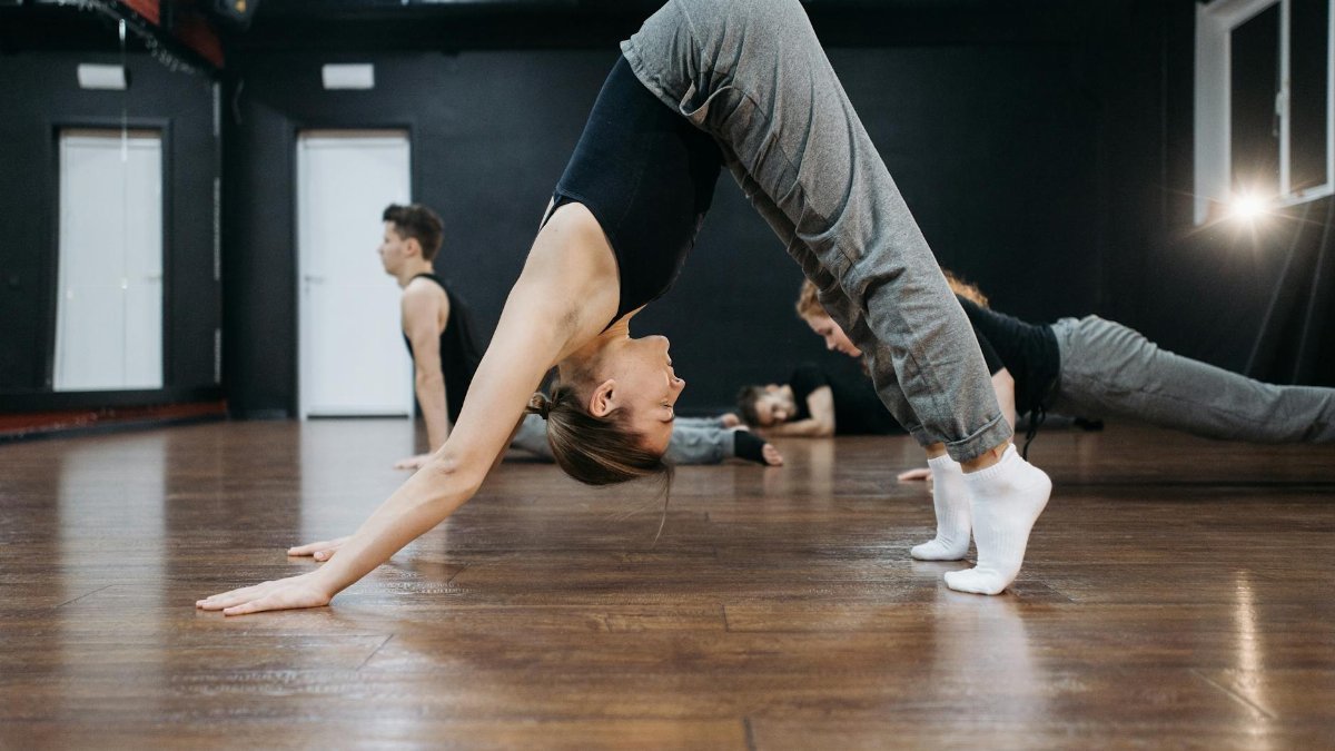 Caucasian woman practicing yoga pose in an indoor dance studio. Group class setting.