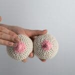 Hand touching knitted yarn breasts for breast cancer awareness campaign.