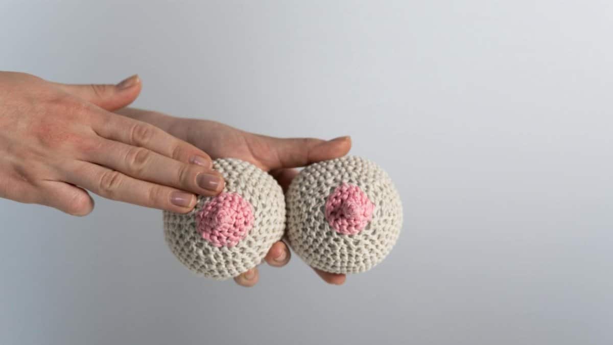 Hand touching knitted yarn breasts for breast cancer awareness campaign.