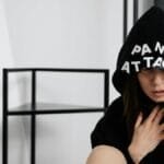 A woman in a hoodie with panic attack letters, representing mental health struggles.