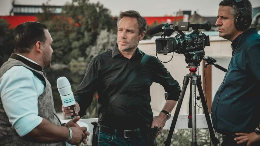 Outdoor interview with a professional news crew capturing footage using high-tech equipment.