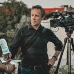 Outdoor interview with a professional news crew capturing footage using high-tech equipment.