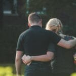 A couple embraces while walking in a sunlit park, conveying love and togetherness.