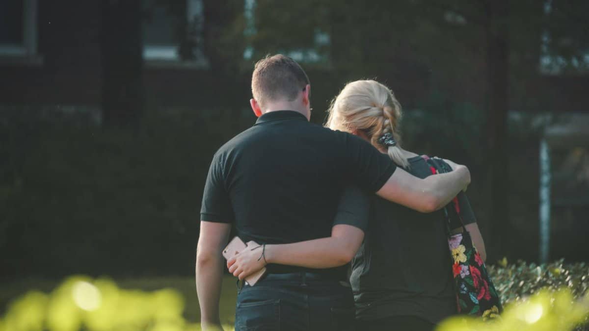 A couple embraces while walking in a sunlit park, conveying love and togetherness.