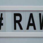 Close-up of a lightbox displaying the hashtag RAW on a white background.