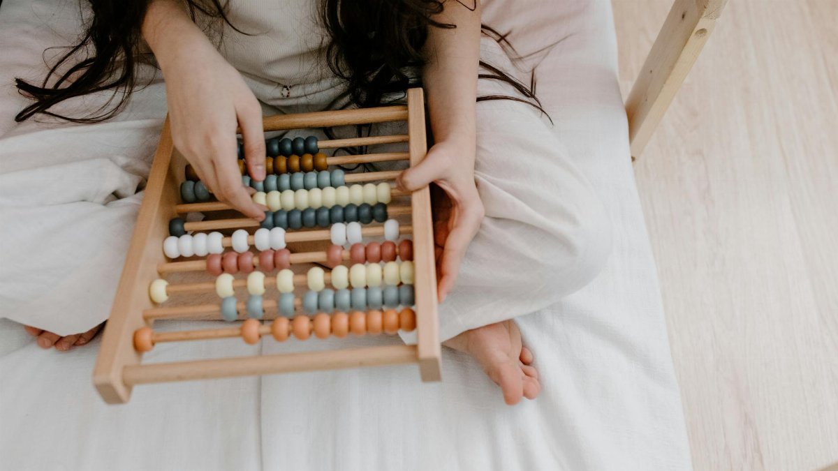 A child using a colorful abacus to learn math in a cozy indoor setting.
