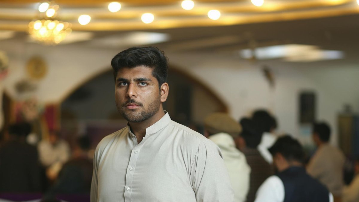 Young man in traditional attire at a social gathering in Sheikhupura, Pakistan.