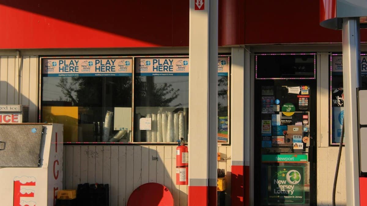 Convenience store entrance at a gas station featuring lottery signs in Bridgeton, New Jersey.