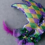 Closeup of a colorful Mardi Gras mask with vibrant purple, green, and gold decorations