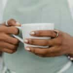 A barista wearing an apron holds a white coffee mug, showcasing contemporary café culture.