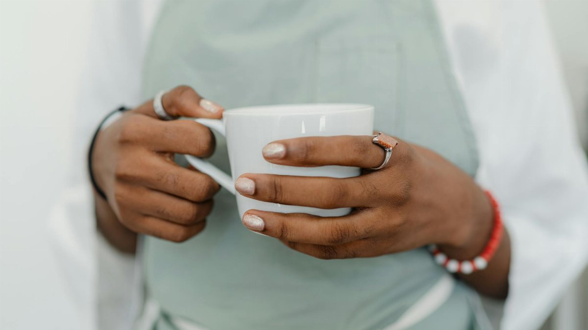A barista wearing an apron holds a white coffee mug, showcasing contemporary café culture.