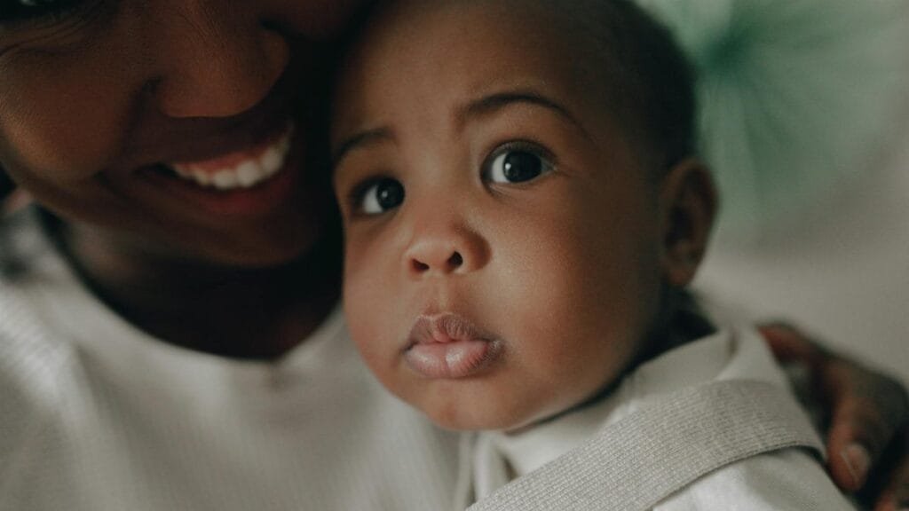 African American mother lovingly holds her baby, showcasing a close-up of faces filled with tenderness.