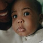 African American mother lovingly holds her baby, showcasing a close-up of faces filled with tenderness.