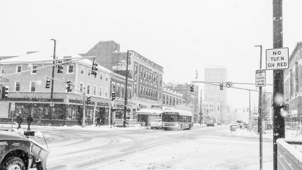 Snow-covered urban street scene in Cambridge, Massachusetts during winter snowfall.