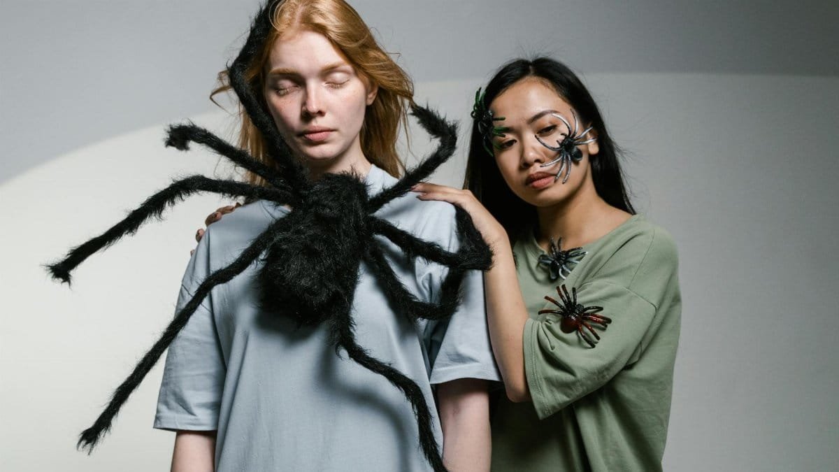 Portrait of two women with faux spiders, exploring themes of fear and anxiety.