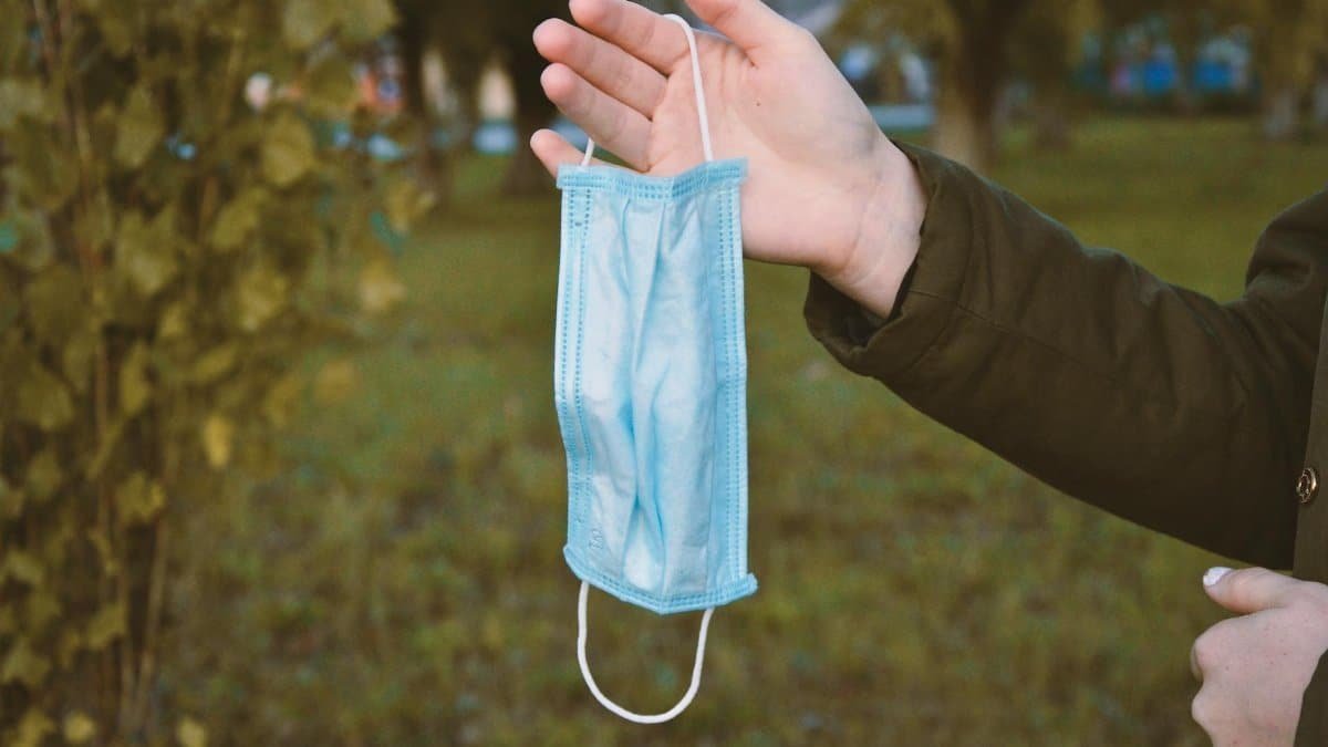 A person holds a blue face mask outside, highlighting health and safety.