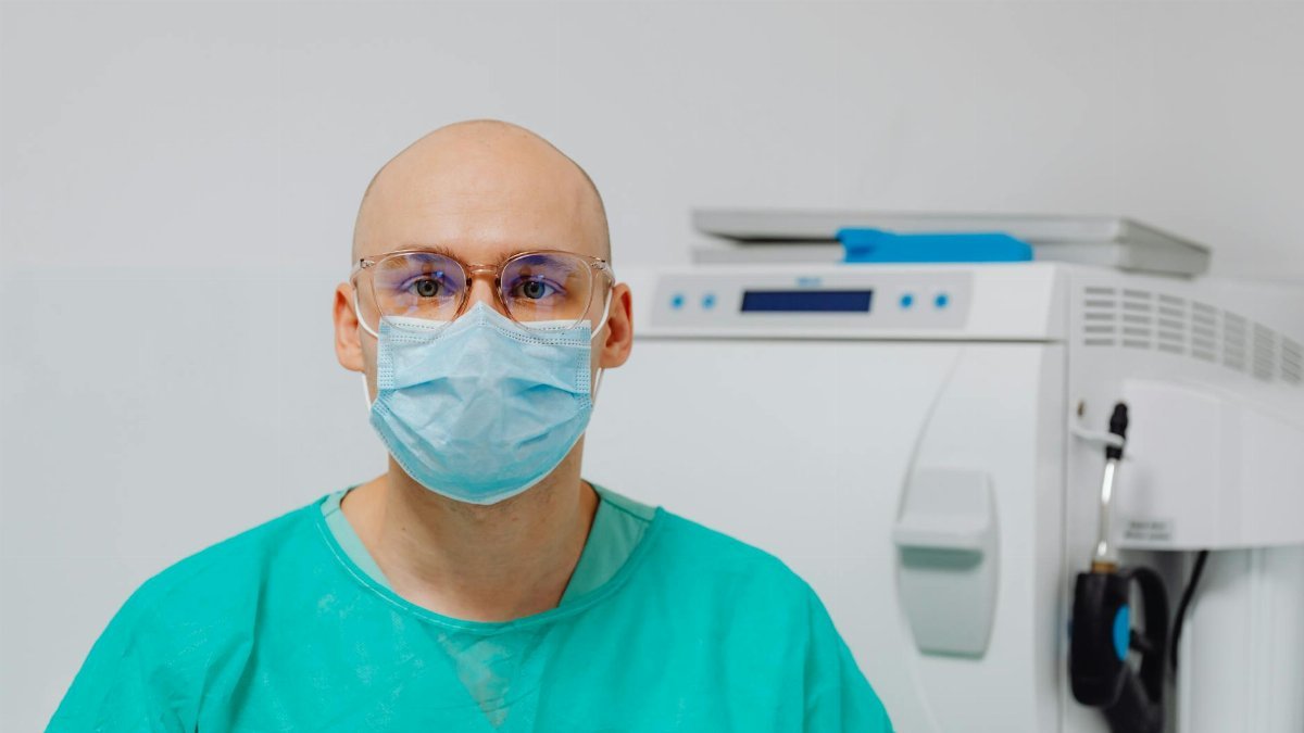 Bald medical professional wearing PPE in a clinic, showcasing safety protocols in healthcare environments.