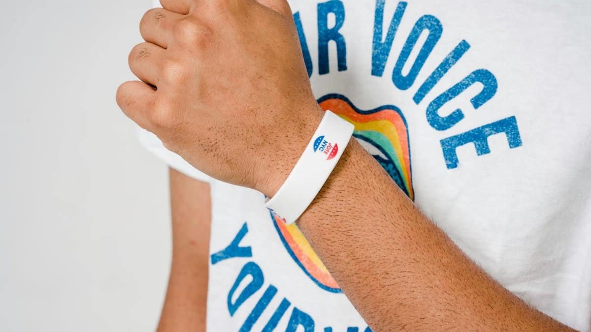 Person wearing a white 'I Voted' wristband and a shirt with 'Your Voice' text.