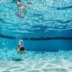 Underwater photo capturing a boy swimming in a clear blue pool, creating ripples.