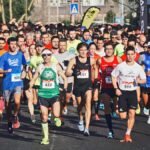 A large group of marathon runners competes outdoors in broad daylight, showcasing endurance and fitness.