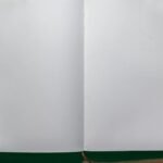 A top-down view of an open blank notebook on a wooden desk, perfect for design or writing projects.