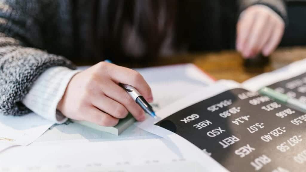 Close-up of a woman reviewing financial documents with focus on numbers and calculations.
