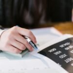 Close-up of a woman reviewing financial documents with focus on numbers and calculations.