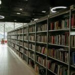 A quiet modern library interior with bookshelves and bright circular lights.