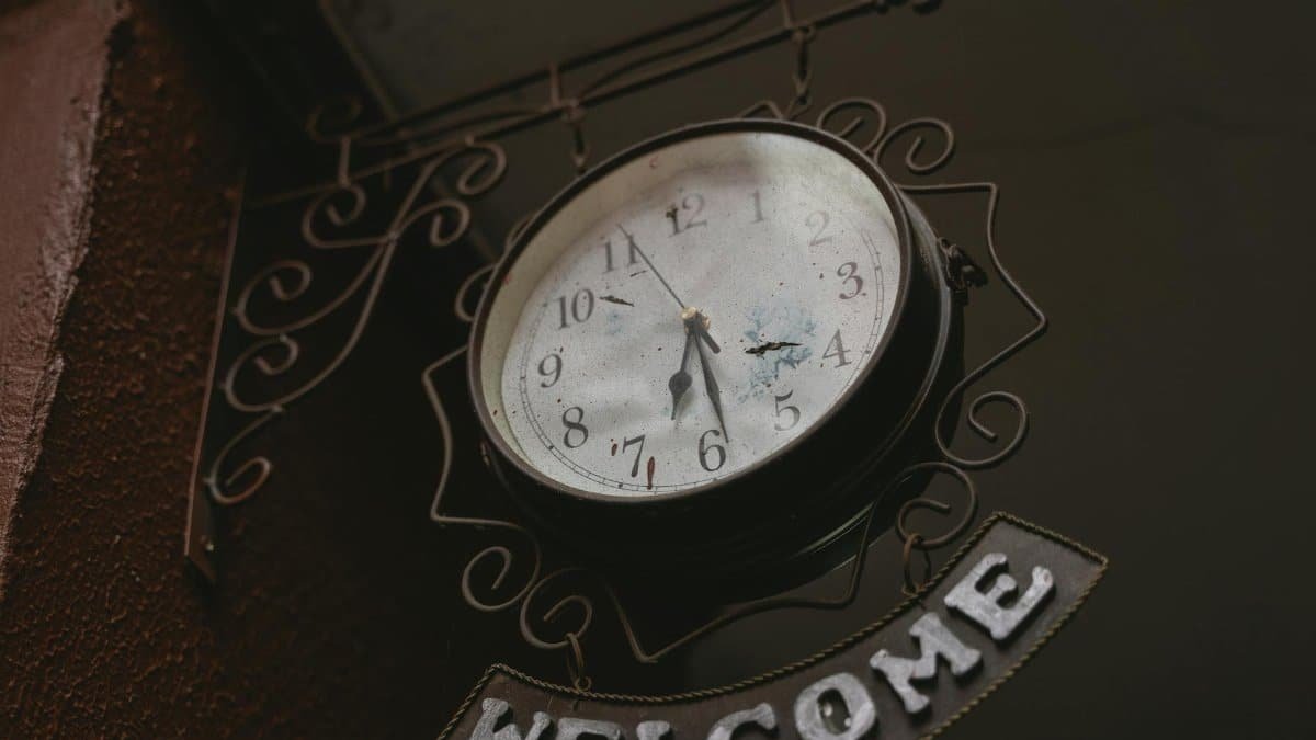 A nostalgic vintage clock with a welcoming sign captured in a low angle shot.