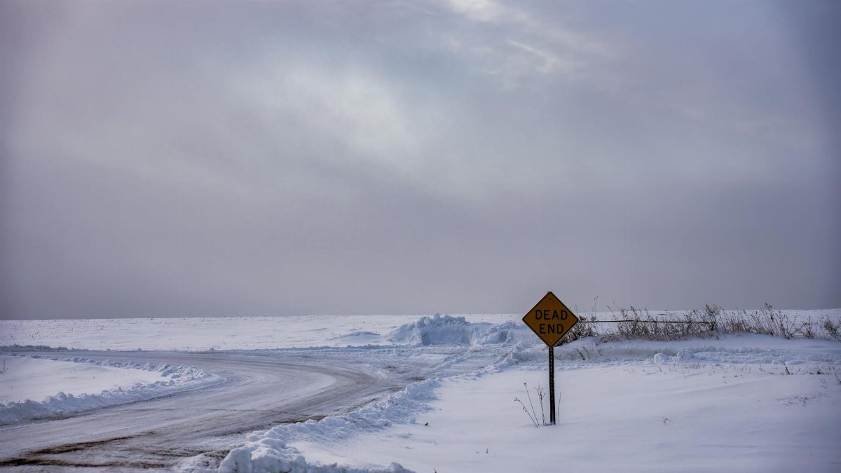 A snowy winter landscape with a dead end sign on a rural road in Minnesota, USA.