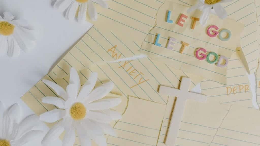 Uplifting flat lay featuring daisies, a cross, and the phrase 'Let Go, Let God'. Perfect for serenity and faith themes.