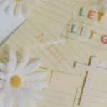 Uplifting flat lay featuring daisies, a cross, and the phrase 'Let Go, Let God'. Perfect for serenity and faith themes.