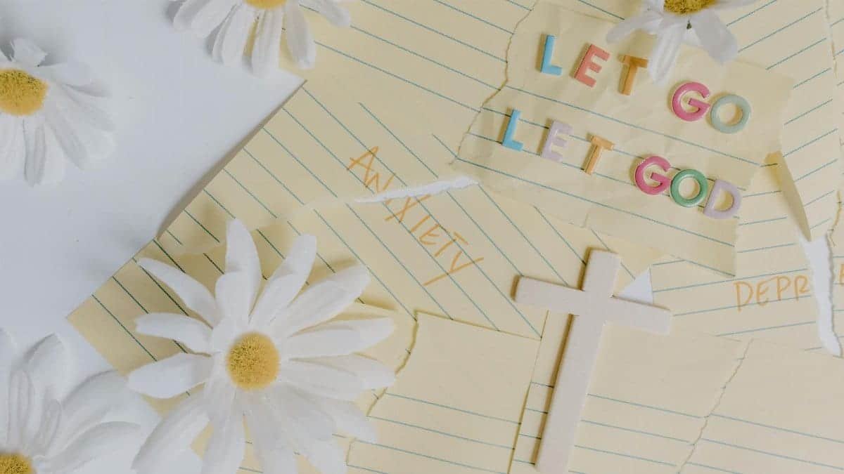 Uplifting flat lay featuring daisies, a cross, and the phrase 'Let Go, Let God'. Perfect for serenity and faith themes.