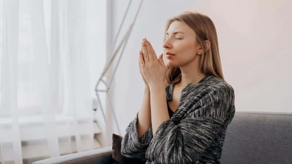 A woman meditates peacefully indoors, seeking relaxation and inner peace through mindful practices.