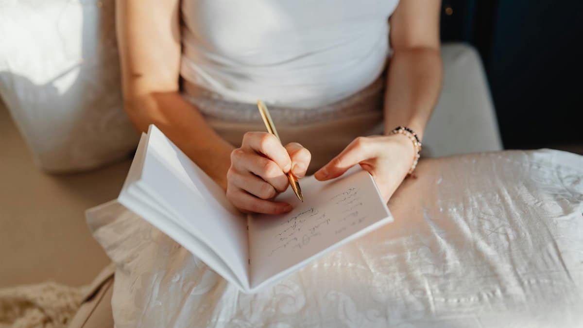 Close-up of a woman writing in a journal while sitting comfortably indoors.