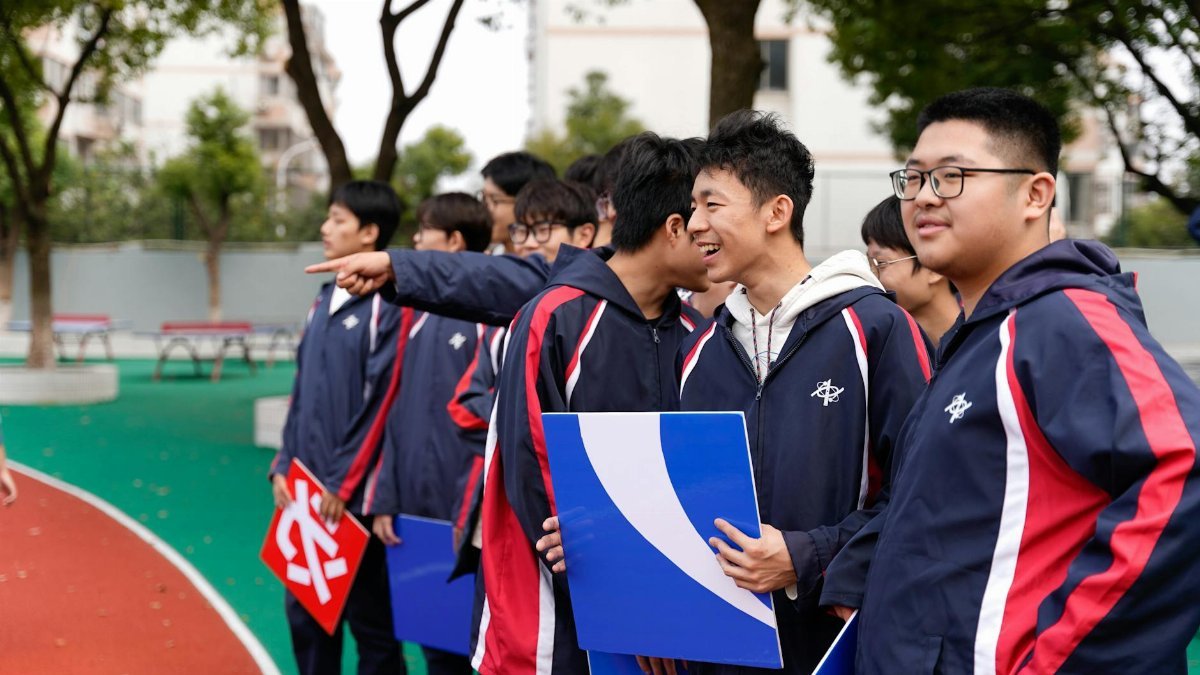 Asian students holding signs at an outdoor event in Wuxi, Jiangsu.