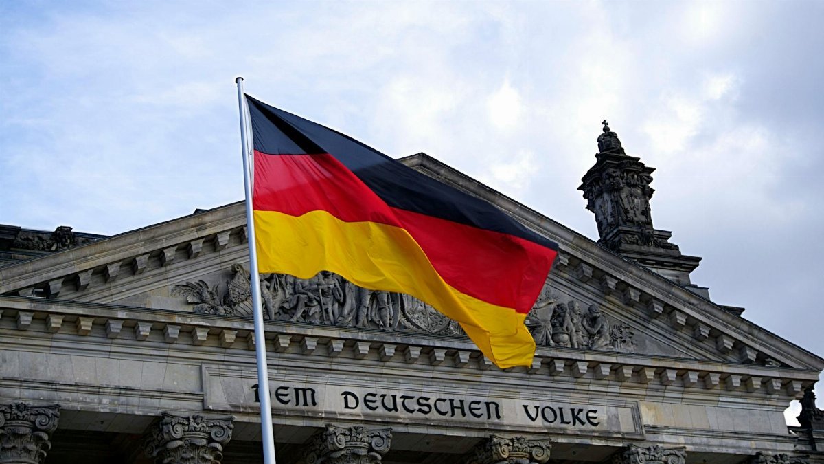 German national flag waving in front of the Reichstag building in Berlin, a symbol of democracy.