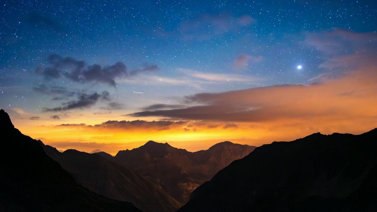 Astrophotography capturing the starry night sky over the majestic mountains of Écrins National Park, France.